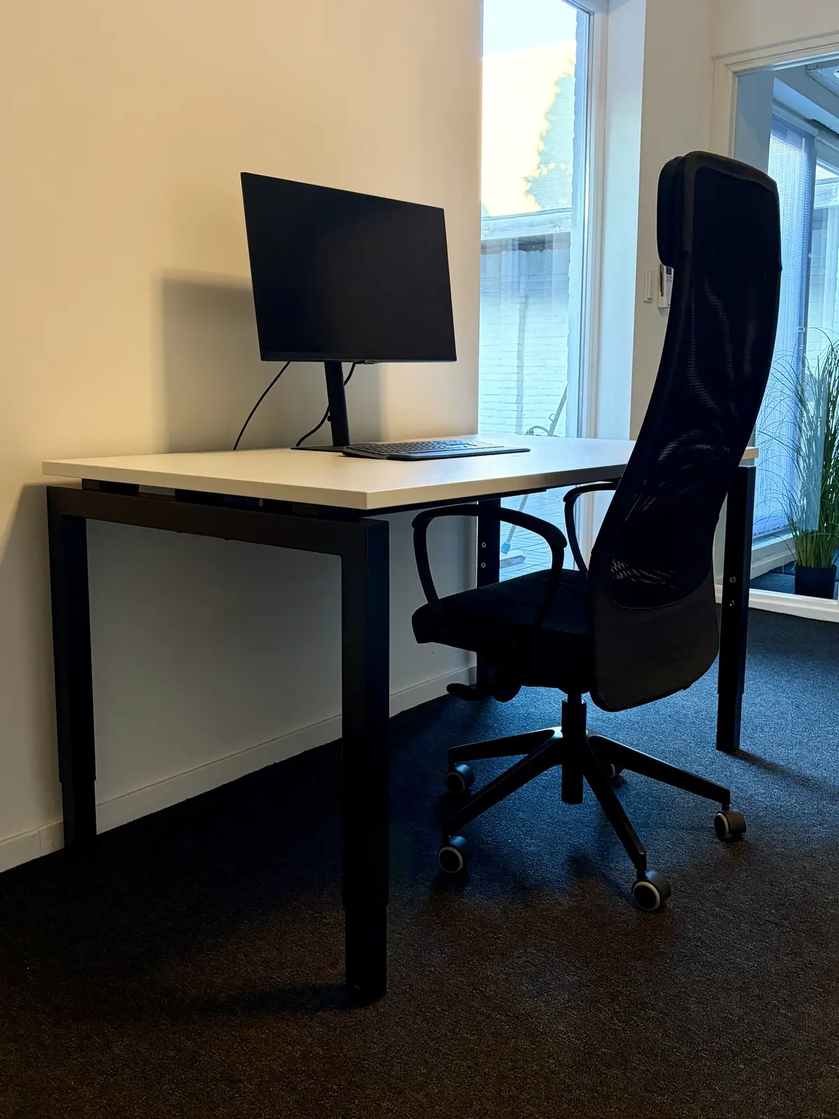 Werkplek in Maastricht met bureau, monitor en bureaustoel bij het raam